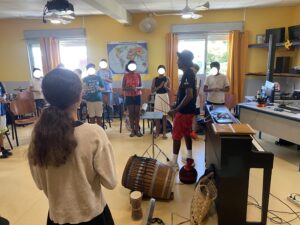 Gramoun Sello, dans la classe de musique, se tient debout avec les élèves pour les faire chanter.