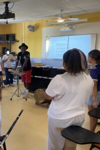 Gramoun Sello, dans la classe de musique, se tient debout avec les élèves pour les faire chanter.