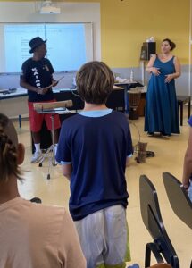 Gramoun Sello, dans la classe de musique, se tient debout avec les élèves pour les faire chanter.