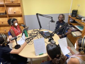 Gramoun Sello, au studio radio, devant son micro est interviewé par 4 élèves.