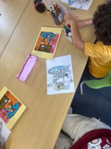 Un élève de maternelle en T-shirt jaune fait du coloriage.