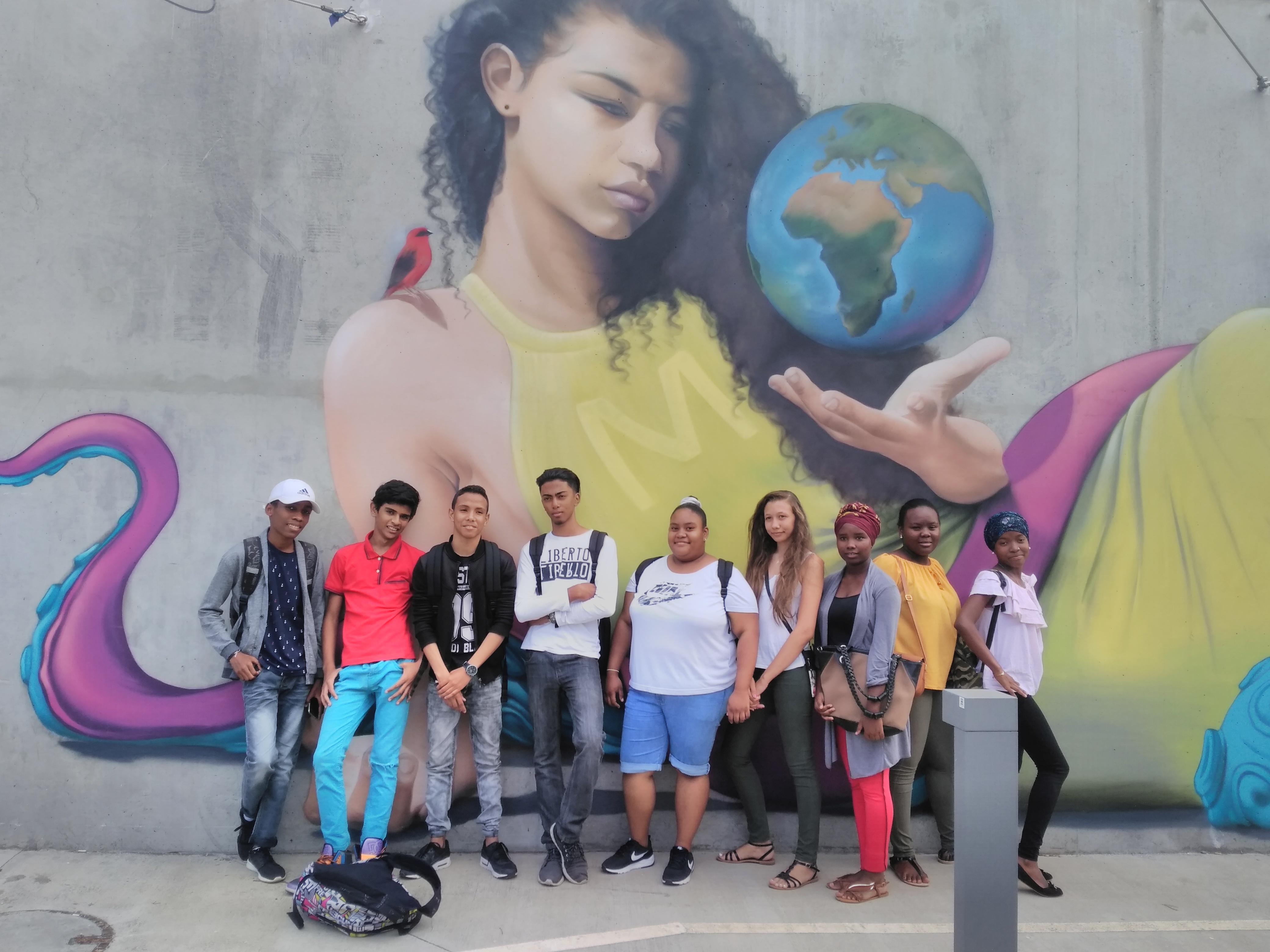groupe d'élèves posant devant une murale des murs extérieurs de la cité des arts